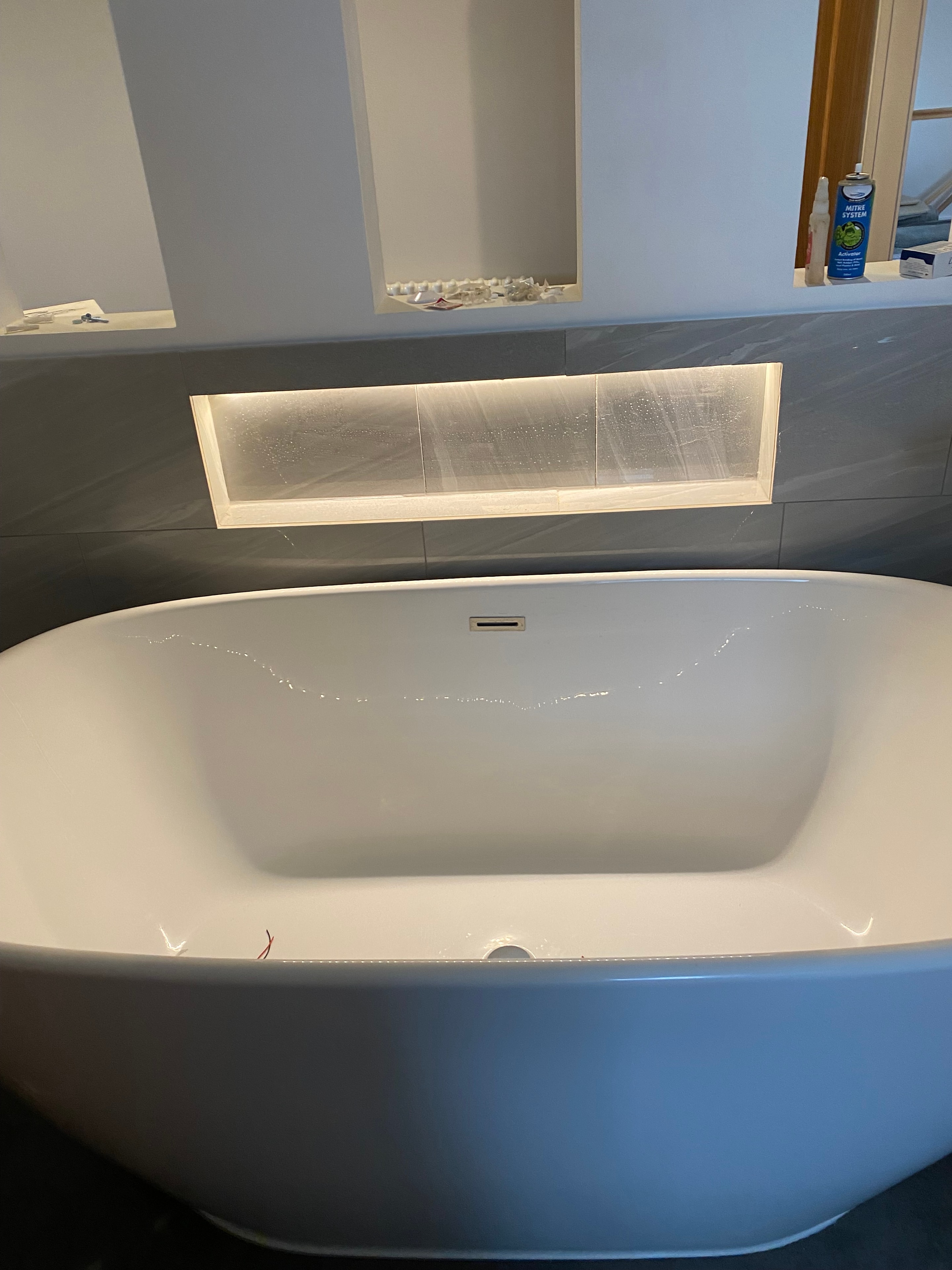 Illuminated bathroom niche beside freestanding bath