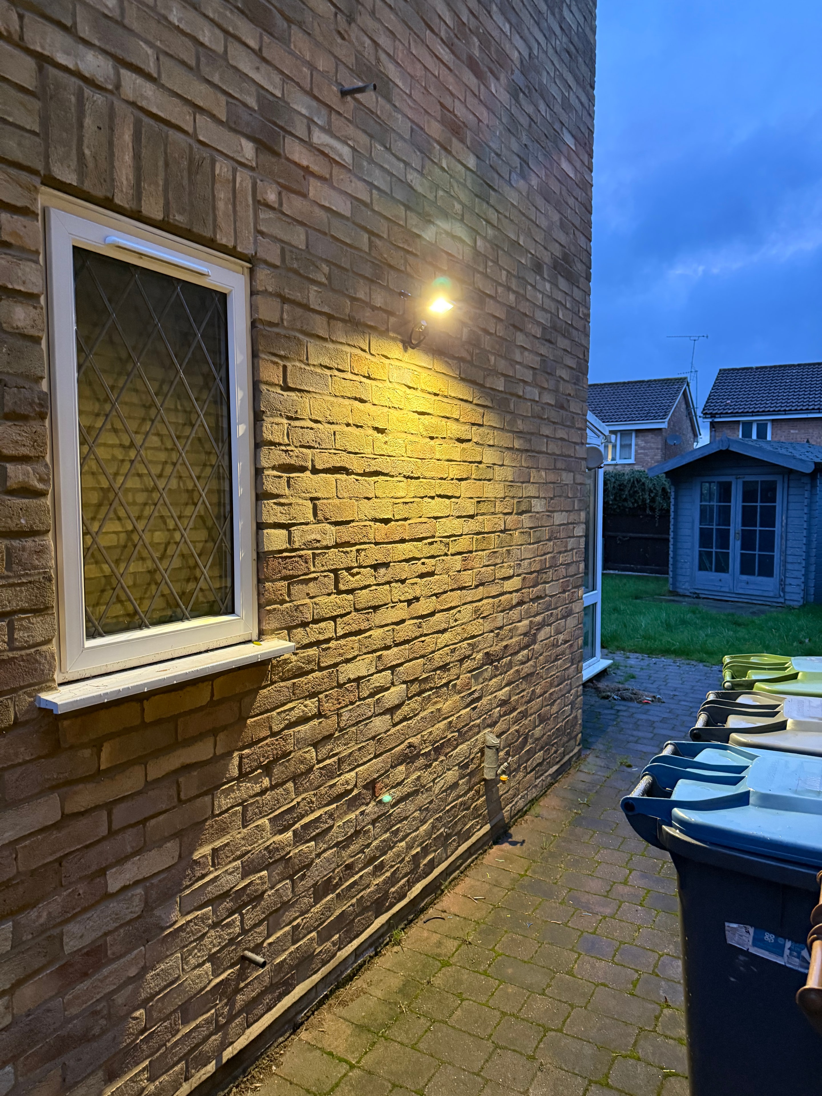 Brick wall exterior with security light illuminated at night