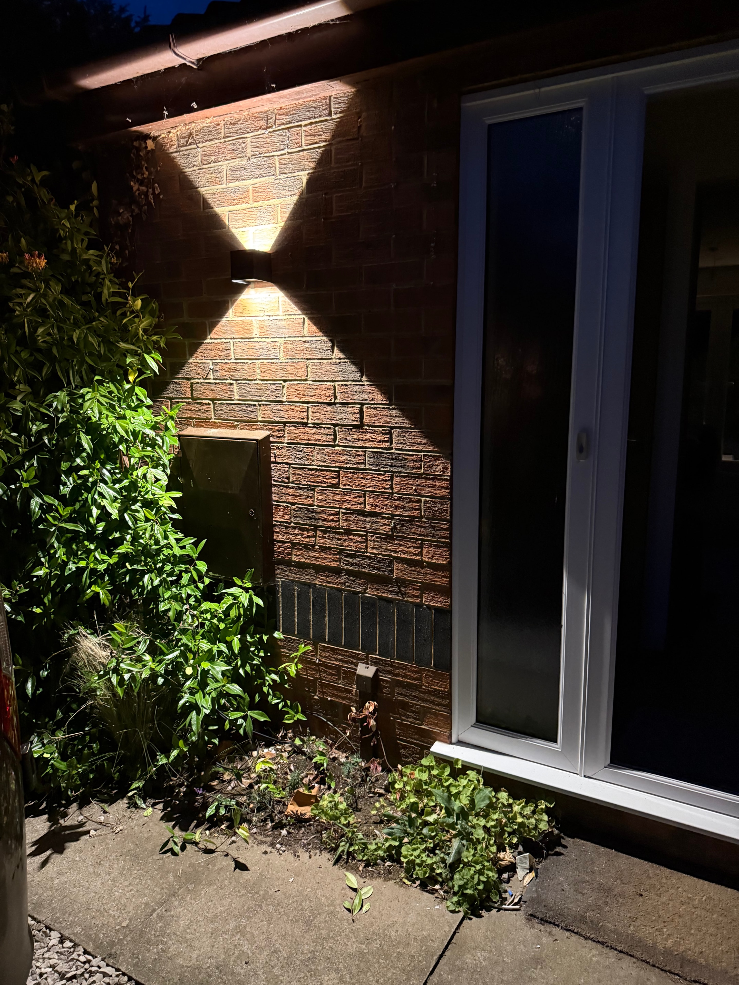 Exterior wall light casting diamond shadow pattern on brick