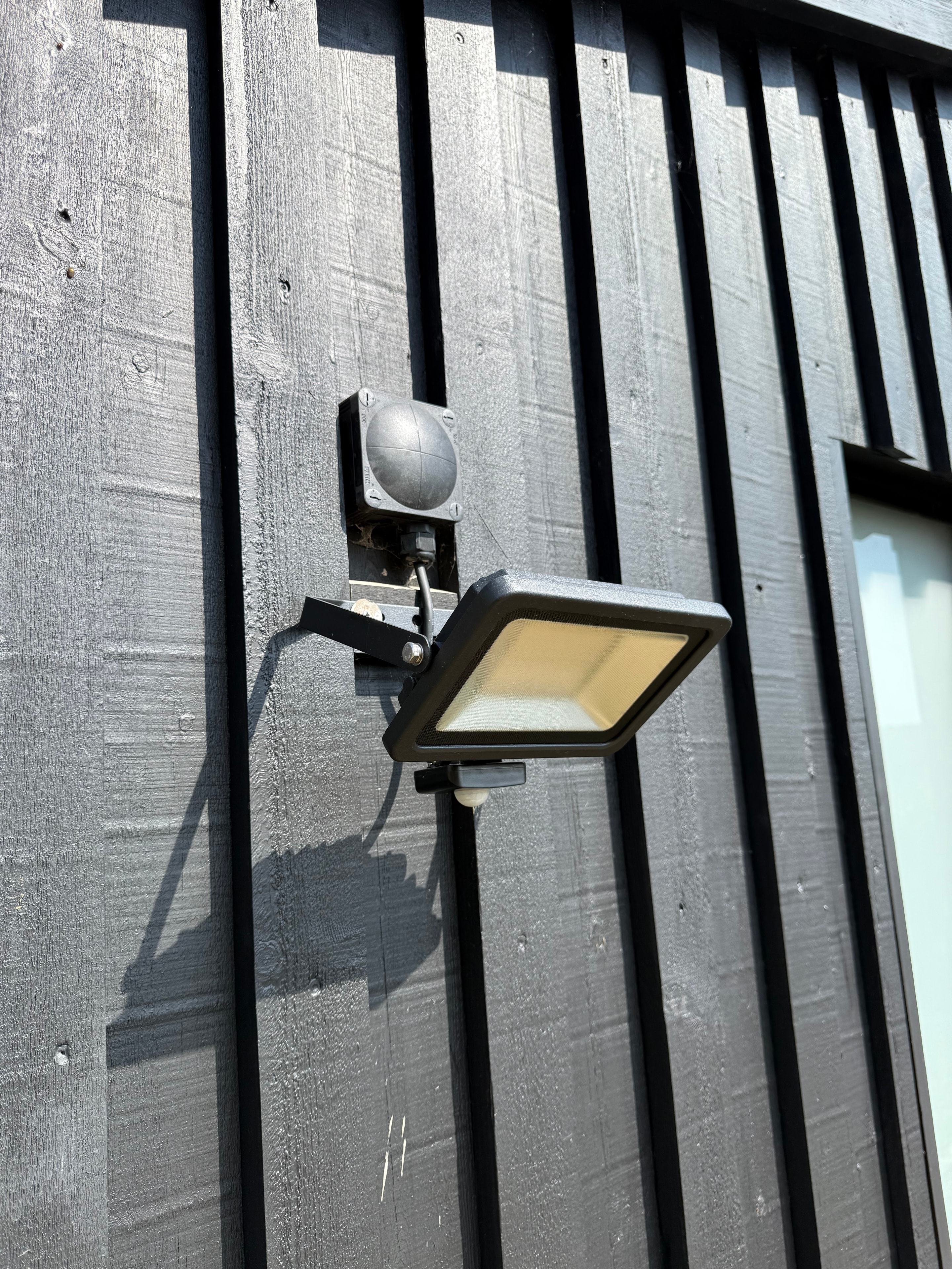 Exterior motion sensor floodlight on timber cladding