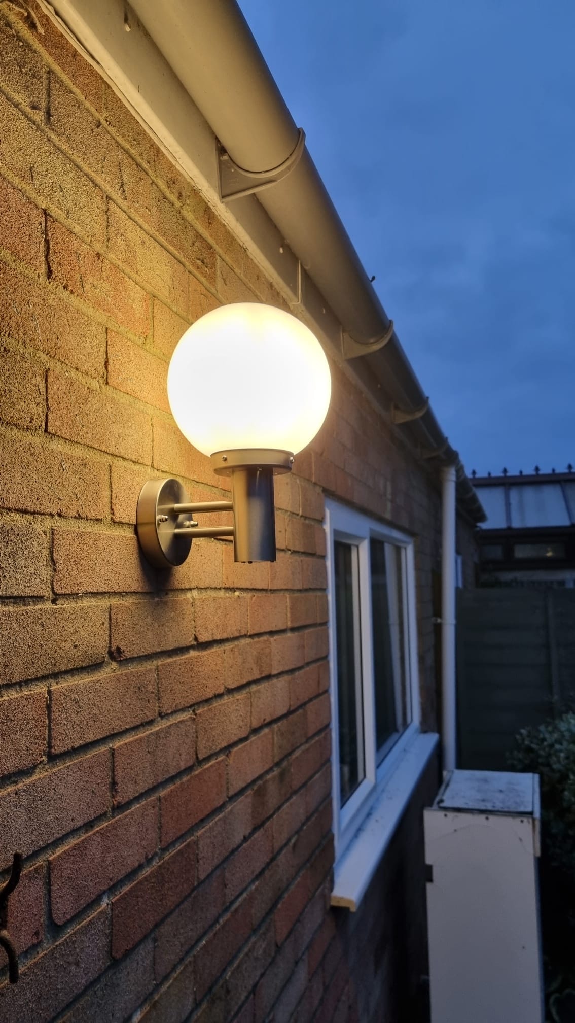 Globe wall light on brick exterior at dusk