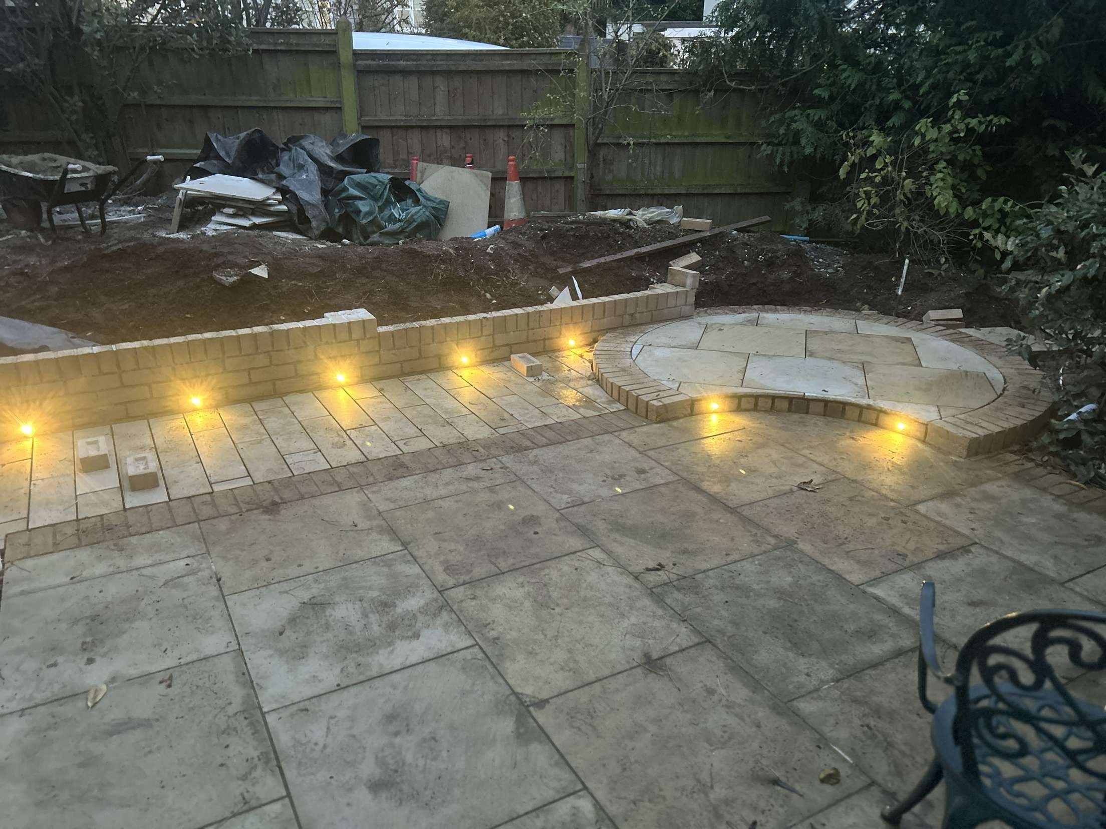 Garden patio with brick wall lights and circular feature